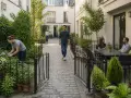 Cour intérieure paisible. Une femme jardine, un homme marche, un couple discute à table. La **servitude non altius tollendi** garantit la vue dégagée.