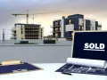Chantier immobilier avec immeubles modernes, grue et panneau "SOLD". Pas de retard livraison VEFA, tout est vendu !