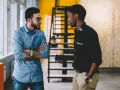 Deux hommes discutent dans un bureau. L'un semble recevoir une mauvaise nouvelle, peut-être une mise à pied sans avertissement.