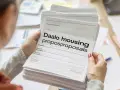 Une personne examine une pile de documents intitulés "Daalo housing proposproposals". Difficile de dire combien de propositions de logement DALO sont incluses.