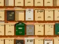 Rangées de boîtes aux lettres de copropriété, certaines jaunes, une verte, une noire et une blanche, avec des numéros et des symboles.
