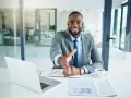 Homme d'affaires souriant, main tendue. Il est assis à son bureau, prêt à conclure un accord, rappelant la jurisprudence sur l'offre d'achat acceptée et la rétractation du vendeur.