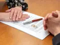 Deux mains se serrent au-dessus d'un contrat, deux alliances posées sur le document. Qui demande le plus le divorce ?
