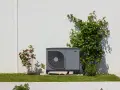 Unité extérieure de pompe à chaleur discrète, entourée de verdure. Un rappel de la jurisprudence sur le bruit des pompes à chaleur.