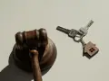 Marteau de juge et clés avec un porte-clés en forme de maison, symbolisant la nouvelle loi sur l'expulsion logement.