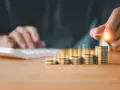 Main qui ajoute une pièce à une pile, symbolisant la croissance de la rémunération variable dans le respect du code du travail.