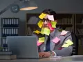 Homme submergé par des post-its, symptômes de burn out. Médecine du travail à considérer.
