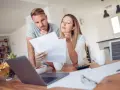 Couple discutent de documents, peut-être une pacs déclaration séparée, devant un ordinateur portable.