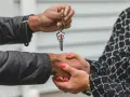 Une main tend une clé de maison, l'autre la saisit. Une poignée de main scelle un accord, peut-être une solution quand un indivisaire ne paye pas.
