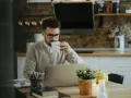 Homme buvant un café devant son ordinateur, pensant à son indemnité transactionnelle CSG CRDS.