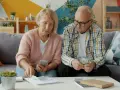 Couple âgé examinant des documents et de l'argent, peut-être pour une déclaration fiscale ou un article 83 CGI.
