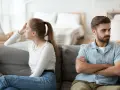 Couple marié, domicile différent, impôt. Ils sont assis sur un canapé, dos à dos, visiblement en désaccord.