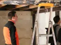 Un homme en veste orange et noire observe le plafond délabré d'un chantier. L'architecte assure le suivi de chantier, une obligation pour garantir la qualité des travaux.