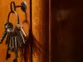 Un trousseau de clés pend à une serrure sur une porte en bois. Ces clés symbolisent la sécurité et la protection, rappelant les lois anti squat.