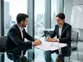 Un homme et une femme en costume discutent de documents. Ils semblent discuter de le piège du licenciement pour inaptitude.