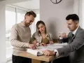 Un couple examine des plans avec un agent immobilier, illustrant l'obligation de l'agent immobilier envers l'acheteur.