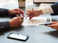 Deux hommes signent un contrat, l'un remettant les clés d'un véhicule. Une transaction pour un **gapd bail commercial** est en cours.