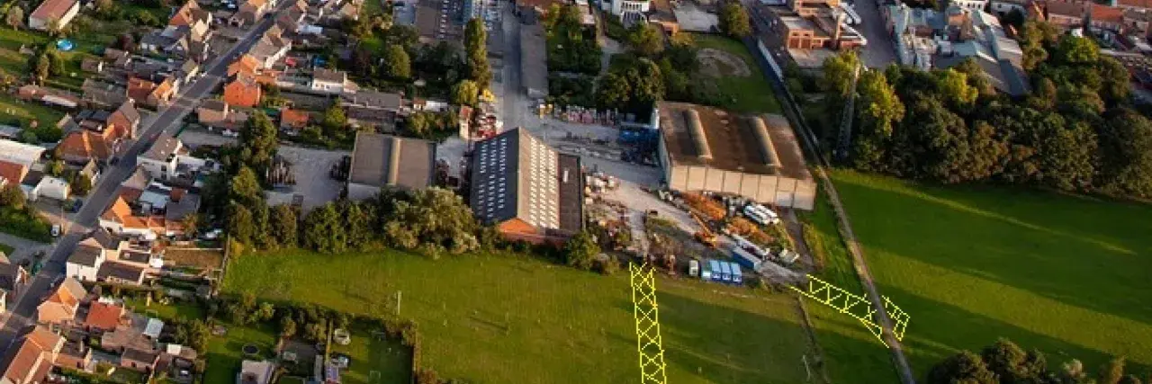 Vue aérienne d'un lotissement et d'une zone industrielle. Un pylône jaune est visible, marquant un emplacement réservé pour le droit de délaissement.