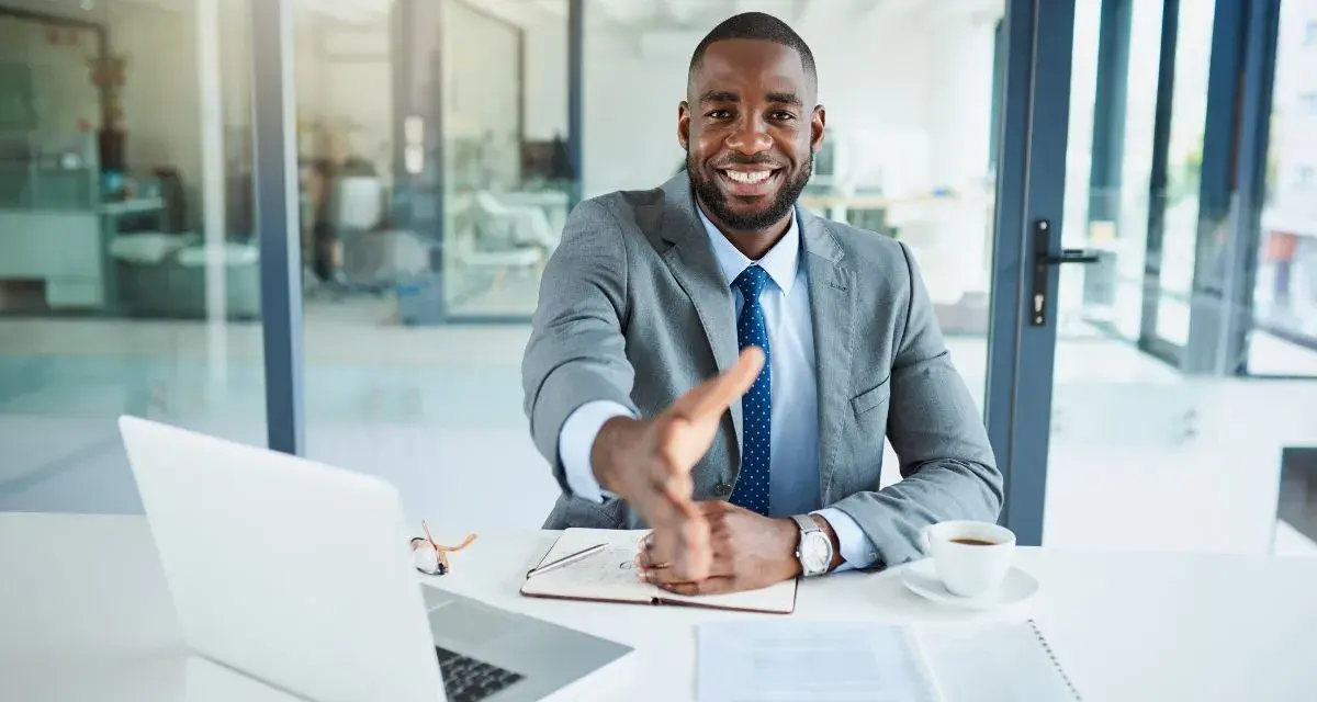 Homme d'affaires souriant, main tendue. Il est assis à son bureau, prêt à conclure un accord, rappelant la jurisprudence sur l'offre d'achat acceptée et la rétractation du vendeur.