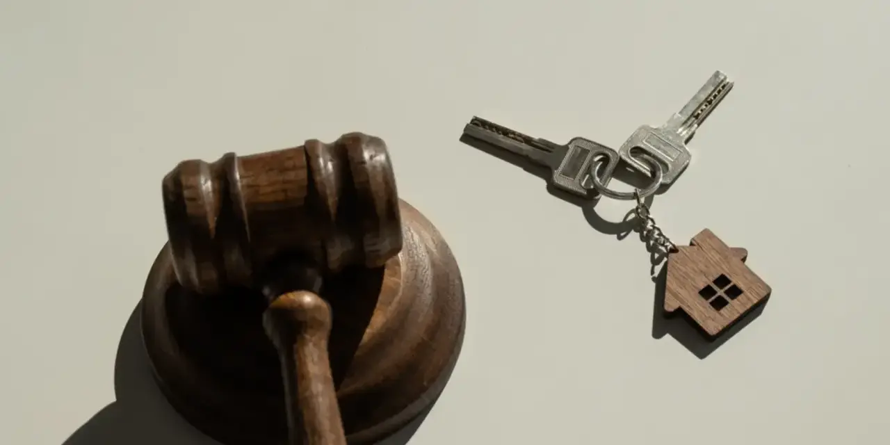Marteau de juge et clés avec un porte-clés en forme de maison, symbolisant la nouvelle loi sur l'expulsion logement.