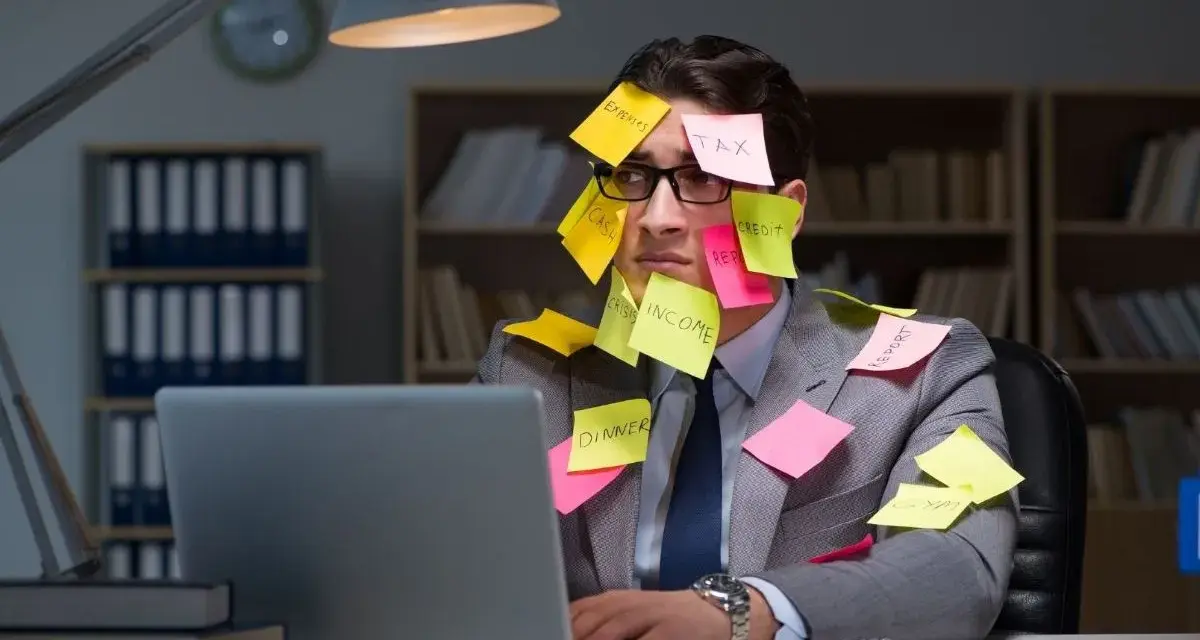 Homme submergé par des post-its, symptômes de burn out. Médecine du travail à considérer.