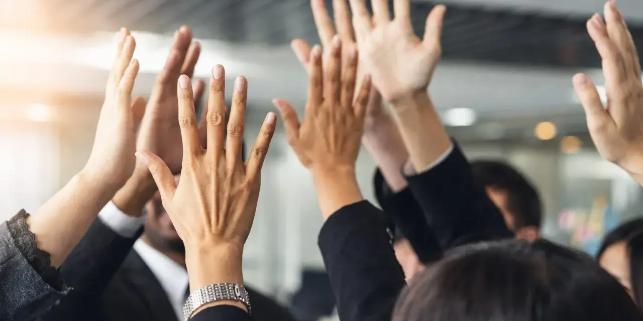 Des mains levées en signe de victoire, célébrant un succès collectif. L'équipe est unie, prête pour le quitus au syndic.