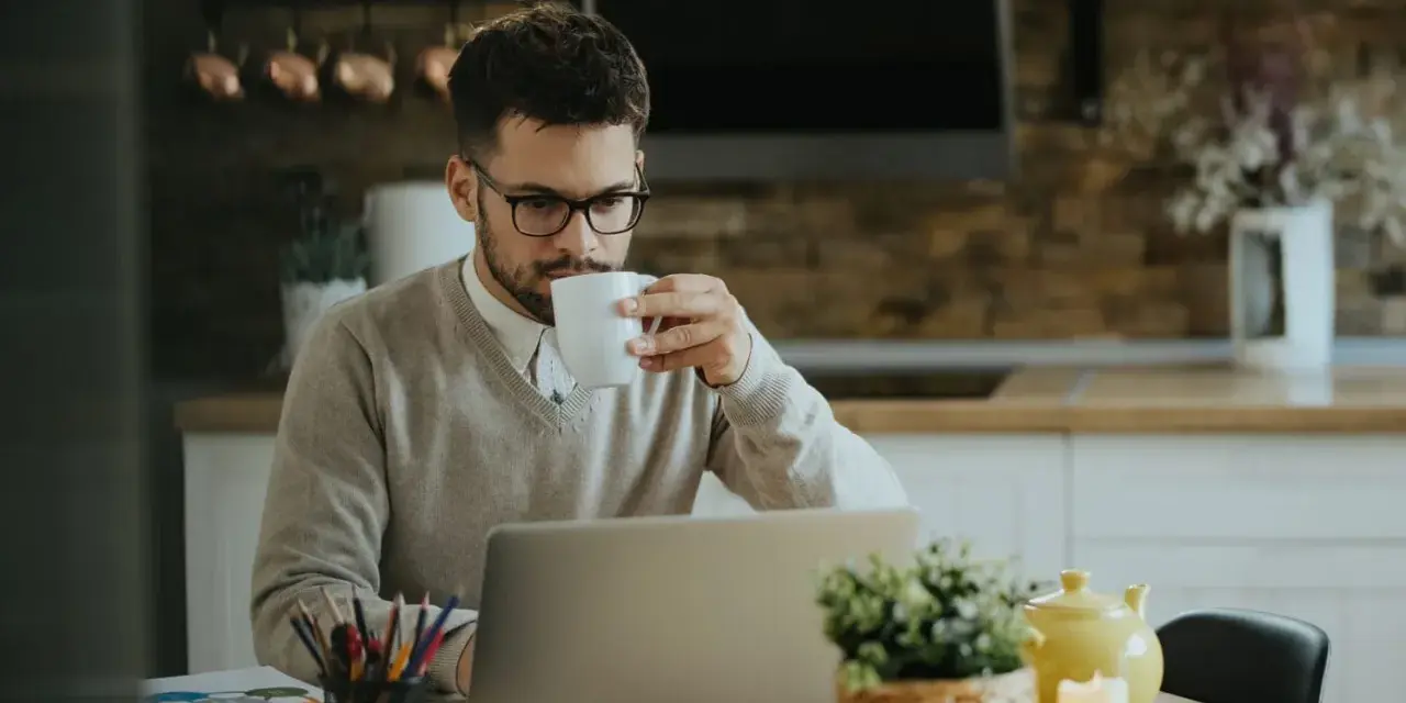 Homme buvant un café devant son ordinateur, pensant à son indemnité transactionnelle CSG CRDS.