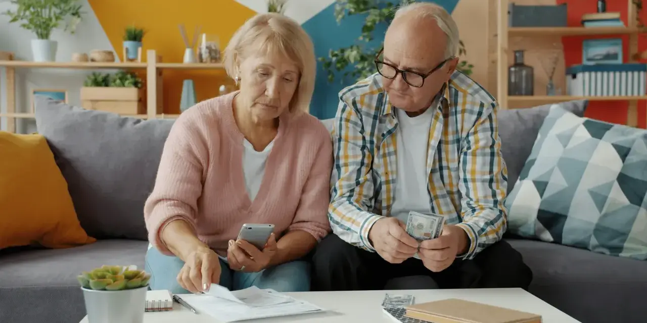 Couple âgé examinant des documents et de l'argent, peut-être pour une déclaration fiscale ou un article 83 CGI.