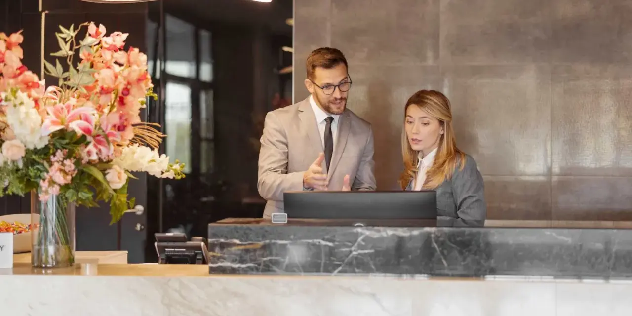 Professionnels discutent d'un calcul d'indemnité d'éviction pour un bail commercial de résidence de tourisme, devant un ordinateur.