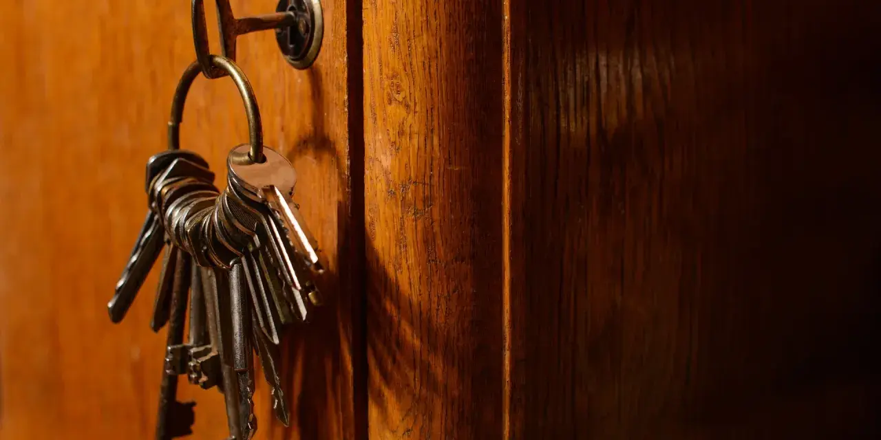 Un trousseau de clés pend à une serrure sur une porte en bois. Ces clés symbolisent la sécurité et la protection, rappelant les lois anti squat.