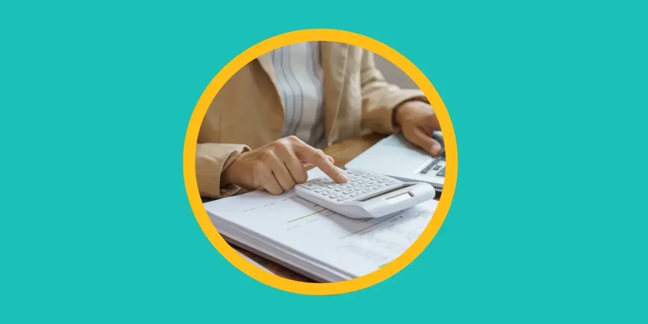 Une personne utilise une calculatrice sur des documents pour apprendre comment payer moins d'impôts.