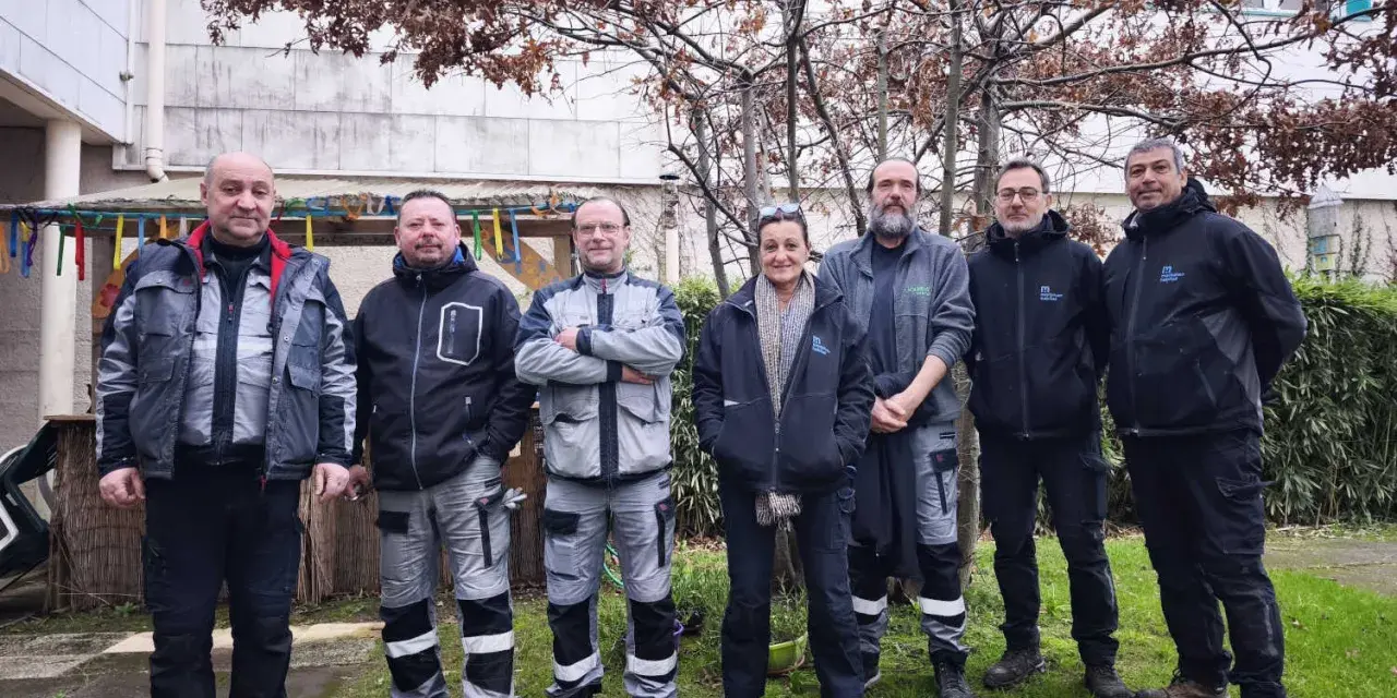 Une équipe de gardiens d'immeuble pose devant un bâtiment, peut-être pour célébrer une nouvelle loi les concernant.