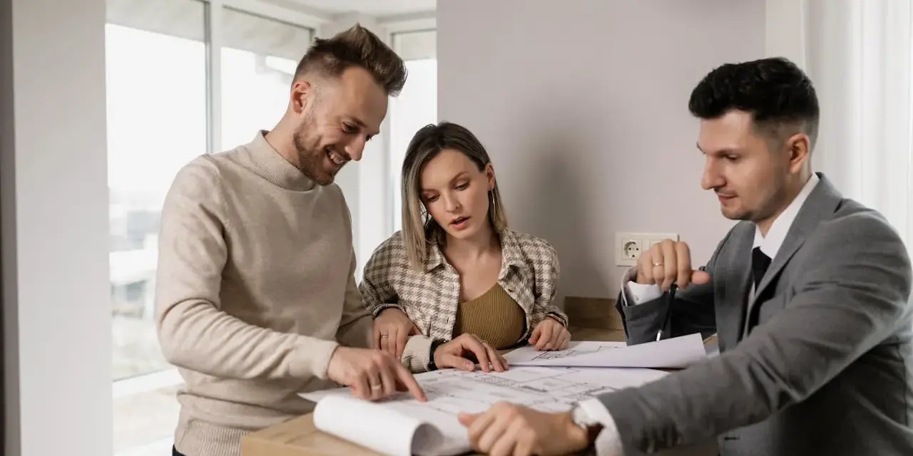 Un couple examine des plans avec un agent immobilier, illustrant l'obligation de l'agent immobilier envers l'acheteur.