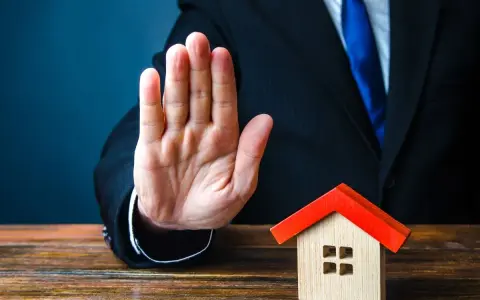 Main tendue, un homme en costume bloque une petite maison. Mon ex refuse la désolidarisation, le bien reste bloqué.