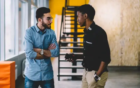Deux hommes discutent dans un bureau. L'un semble recevoir une mauvaise nouvelle, peut-être une mise à pied sans avertissement.
