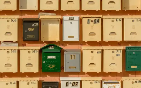 Rangées de boîtes aux lettres de copropriété, certaines jaunes, une verte, une noire et une blanche, avec des numéros et des symboles.