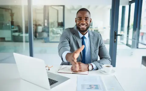 Homme d'affaires souriant, main tendue. Il est assis à son bureau, prêt à conclure un accord, rappelant la jurisprudence sur l'offre d'achat acceptée et la rétractation du vendeur.