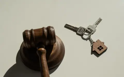 Marteau de juge et clés avec un porte-clés en forme de maison, symbolisant la nouvelle loi sur l'expulsion logement.