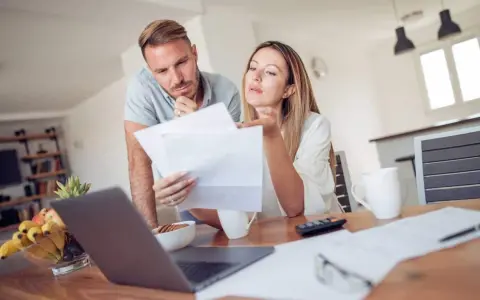 Couple discutent de documents, peut-être une pacs déclaration séparée, devant un ordinateur portable.