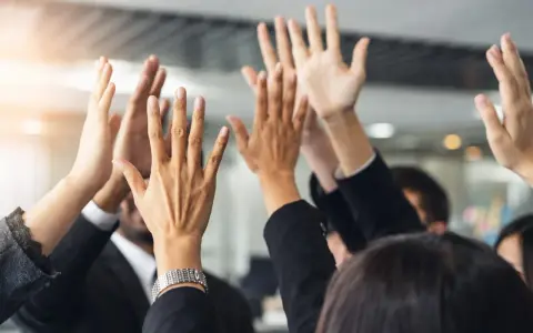 Des mains levées en signe de victoire, célébrant un succès collectif. L'équipe est unie, prête pour le quitus au syndic.