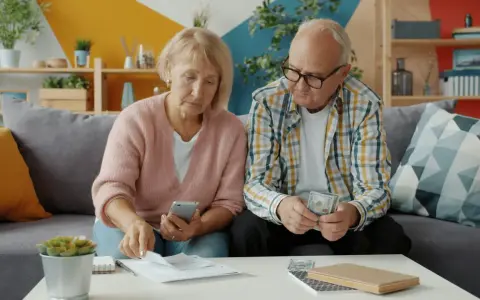 Couple âgé examinant des documents et de l'argent, peut-être pour une déclaration fiscale ou un article 83 CGI.