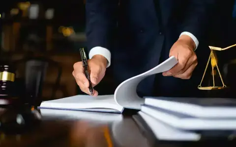 Un avocat examine des documents, une balance de la justice et un maillet sur un bureau. Il semble qu'il soit confronté à une situation où je ne peux pas payer la prestation compensatoire.