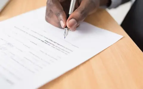 Main noire signant un document, peut-être pour éviter un trouble de jouissance.