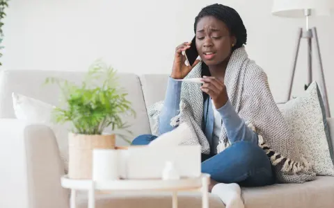 Femme malade au téléphone, thermomètre en main, elle doit se mettre en arrêt maladie avant entretien préalable licenciement.