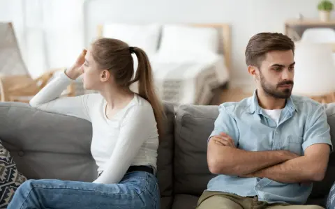 Couple marié, domicile différent, impôt. Ils sont assis sur un canapé, dos à dos, visiblement en désaccord.