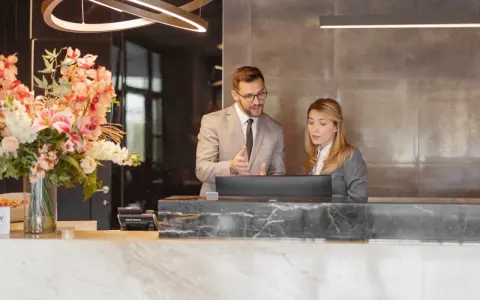 Professionnels discutent d'un calcul d'indemnité d'éviction pour un bail commercial de résidence de tourisme, devant un ordinateur.