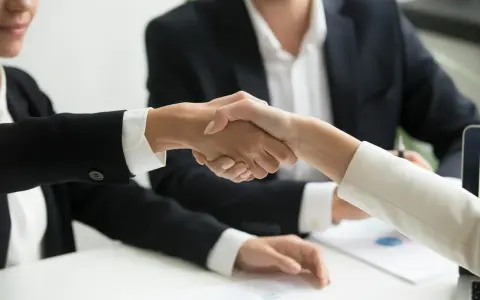 Poignée de main entre deux personnes en costume, symbolisant un accord ou un changement de dirigeant.