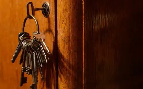 Un trousseau de clés pend à une serrure sur une porte en bois. Ces clés symbolisent la sécurité et la protection, rappelant les lois anti squat.