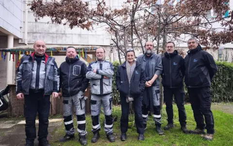 Une équipe de gardiens d'immeuble pose devant un bâtiment, peut-être pour célébrer une nouvelle loi les concernant.