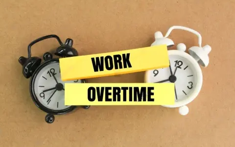 Deux réveils, l'un noir, l'autre blanc, symbolisent les heures supplémentaires non payées.